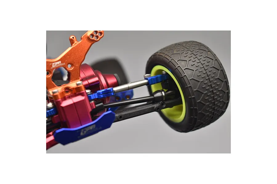 Close-up of an RC car rear suspension assembly featuring a black CVD drive shaft, orange and red aluminum parts, and a tire on a yellow rim.