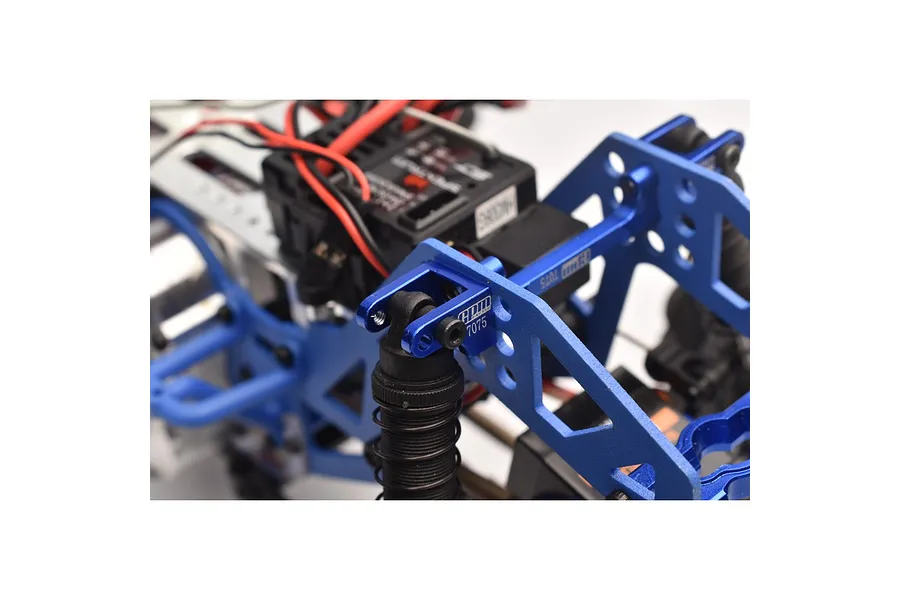 Close-up of a blue anodized aluminium shock mount installed on an RC vehicle chassis, featuring GPM Racing branding.
