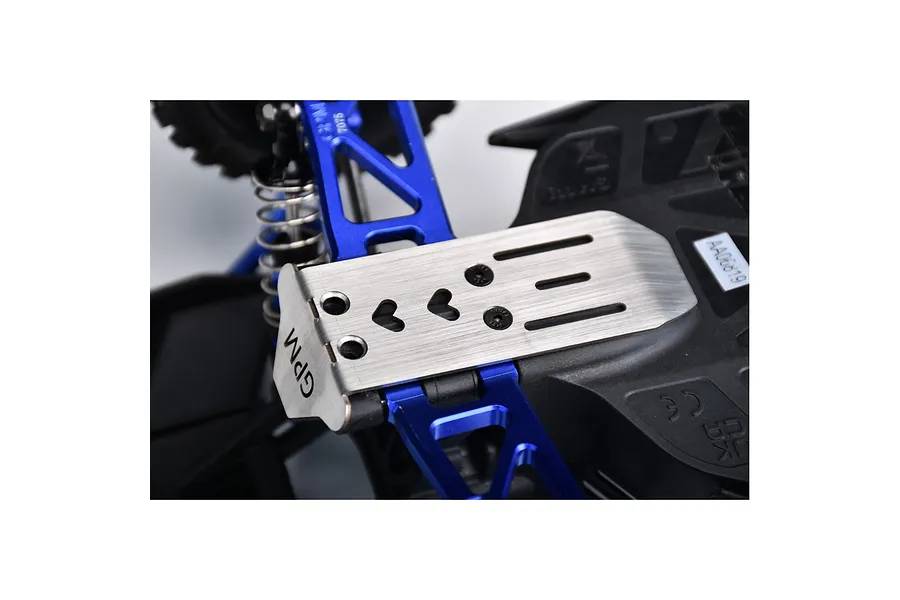 A close-up view of a GPM stainless steel skid plate installed on an RC car chassis, featuring blue aluminum suspension arms and black plastic components.