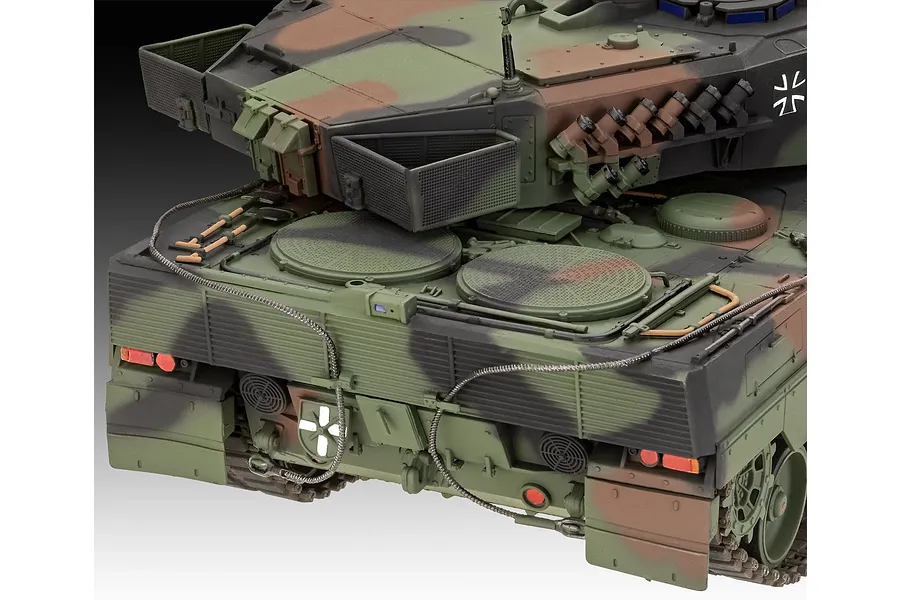 Close-up of the rear deck and turret of a camouflaged Leopard 2A6M+ tank model kit, showing detailed engine grilles, tools, and rear light assemblies.