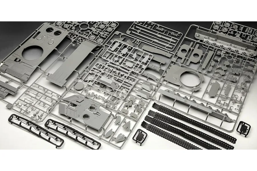 Multiple grey plastic model kit sprues and black rubber tank tracks for a Leopard 2A6M+ tank model, laid out on a white surface.