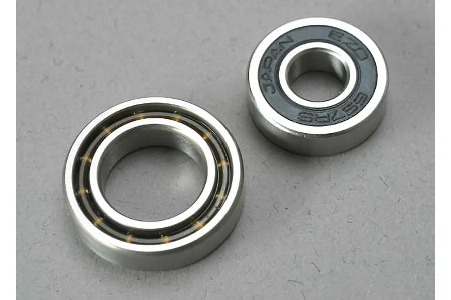Two metal ball bearings of different sizes sitting on a grey surface.