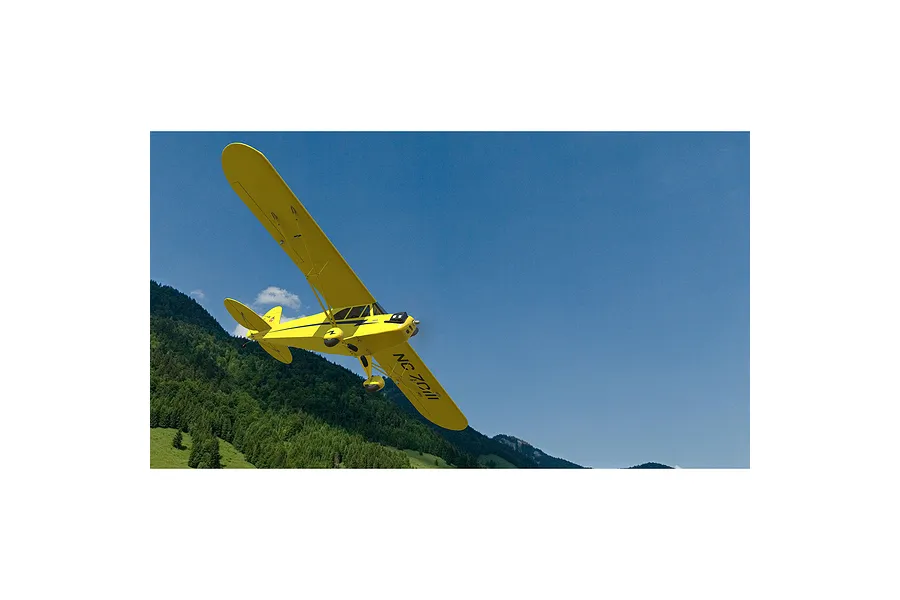 A digital rendering of a bright yellow Piper Cub style RC plane flying against a blue sky and mountain backdrop.