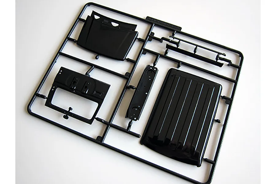 A black plastic sprue frame containing model car parts, including a roof panel and interior components, for a 1/24 scale Suzuki Jimny model kit.