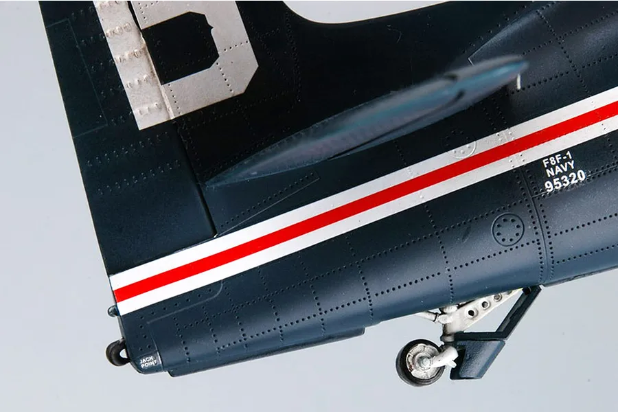 Close-up of the rear fuselage and tail section of a dark blue F8F-1 Bearcat model aircraft with red and white striping and visible panel lines.