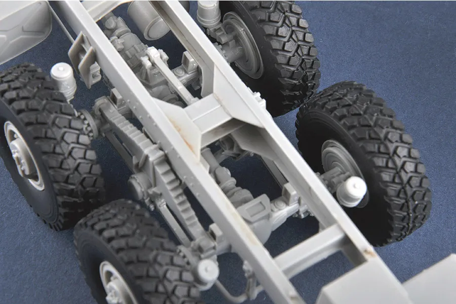 Close-up of the unpainted plastic chassis and suspension assembly of a 1/35 scale military truck model kit.