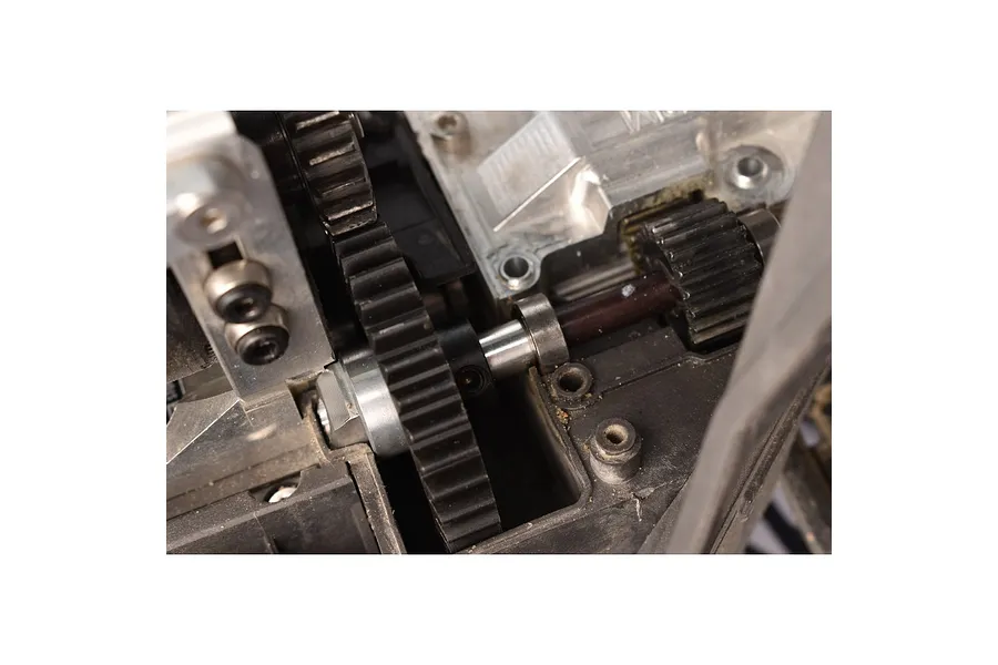 Close-up of a black metal spur gear installed in an RC car drivetrain assembly.
