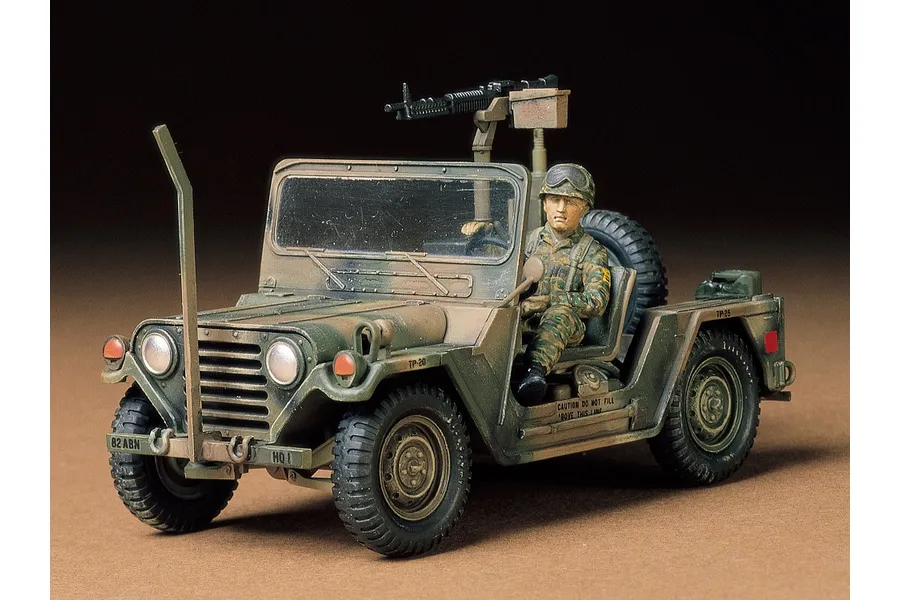 A fully assembled and painted 1/35 scale Tamiya M151A2 Ford Mutt model truck with a soldier figure and mounted machine gun.