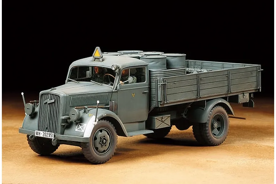 A 1/35 scale model of a German 3-ton cargo truck, painted in field grey, featuring a flatbed with barrels and two figures in the cab.