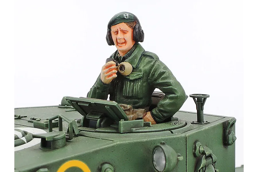 A painted 1/35 scale plastic model tank commander figure emerging from the hatch of a green British Cromwell tank model.
