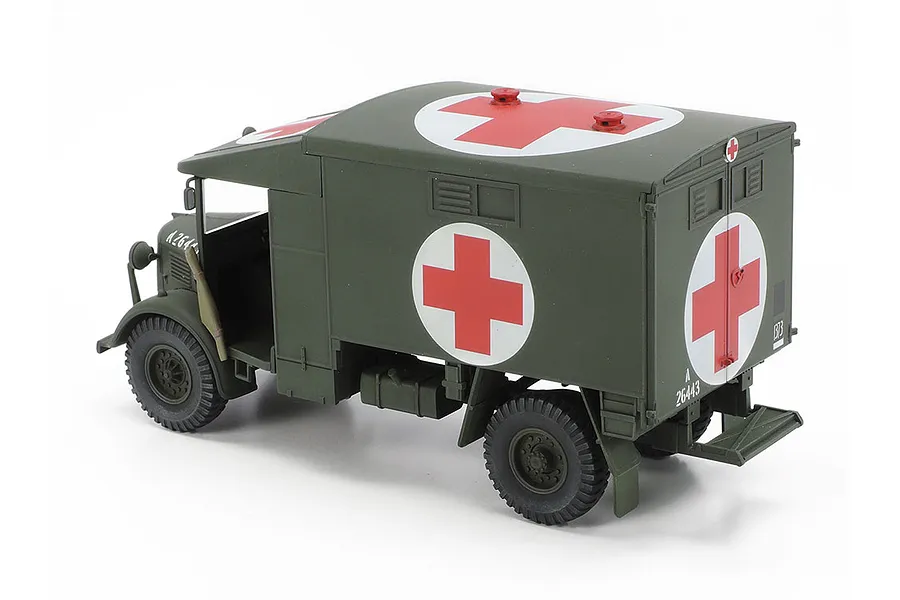 A 1/48 scale Tamiya model of a British Austin K2 ambulance painted in olive drab with prominent red cross markings on a white background.