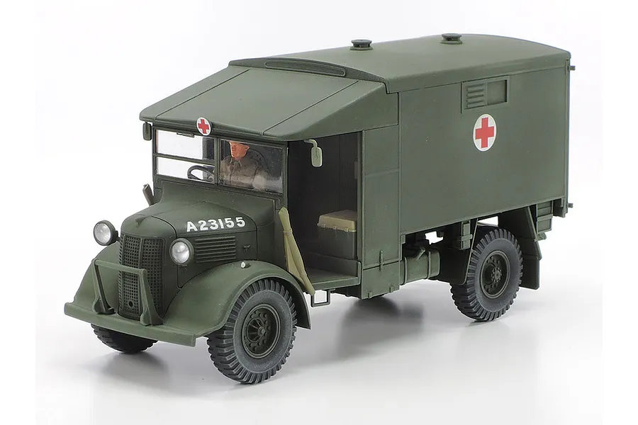 A 1/48 scale plastic model of a British Austin K2 ambulance painted in olive drab with red cross markings and a driver figure inside.