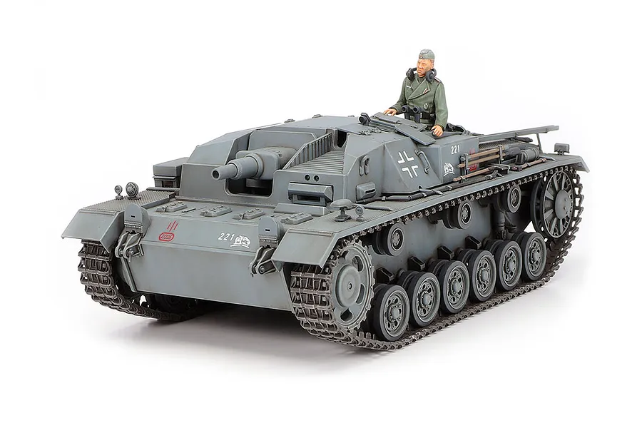 A fully assembled and painted 1/35 scale Tamiya German Sturmgeschutz III Ausf.B model tank with a crew figure in the hatch.