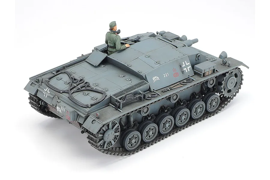 A high-angle rear view of a Tamiya 1/35 scale German Sturmgeschutz III Ausf.B plastic model tank with a crew figure, painted in grey.