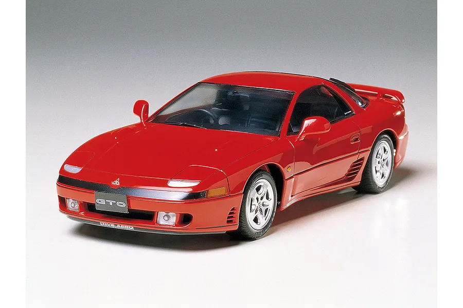 A high-angle studio shot of a red Tamiya 1/24 scale Mitsubishi GTO model car on a white background.