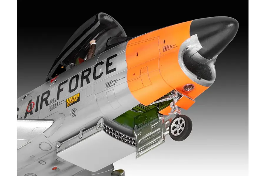 Close-up of a 1/48 scale Revell F-86D Dog Sabre model aircraft showing the silver fuselage, orange nose section, and open rocket tray.