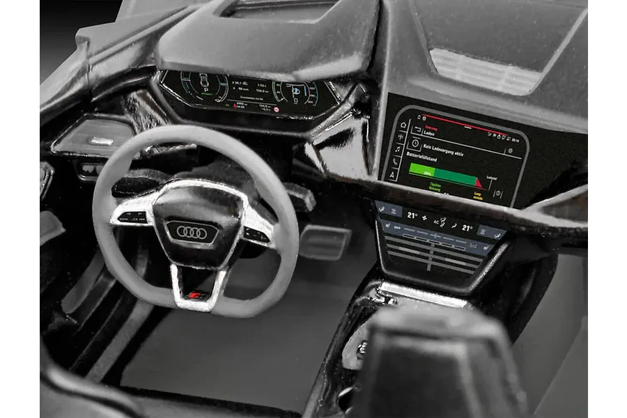 Close-up of the detailed interior cockpit of a Revell 1/24 scale Audi E-Tron GT plastic model car, showing the steering wheel, dashboard, and infotainment screen.