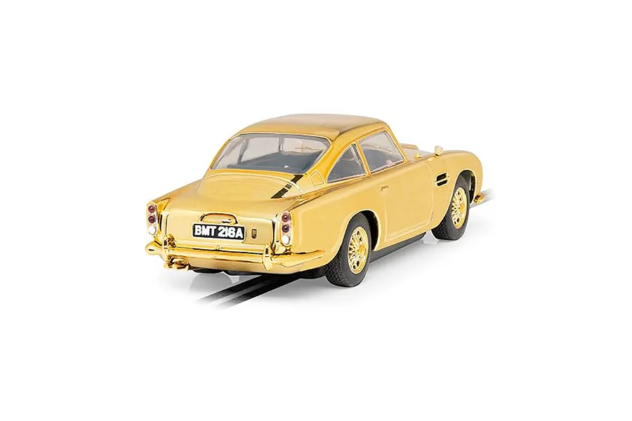 A rear three-quarter view of a gold-plated Scalextric 1/32 scale Aston Martin DB5 slot car with BMT 216A license plate on a white background.
