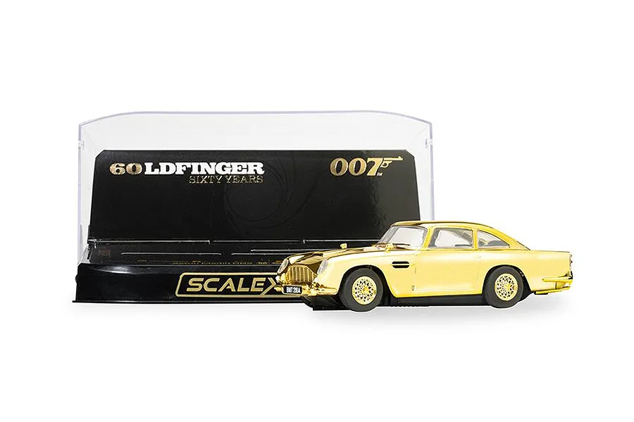A gold-plated Scalextric 1/32 scale Aston Martin DB5 slot car from the Goldfinger 60th Anniversary edition, displayed in front of its branded display case.
