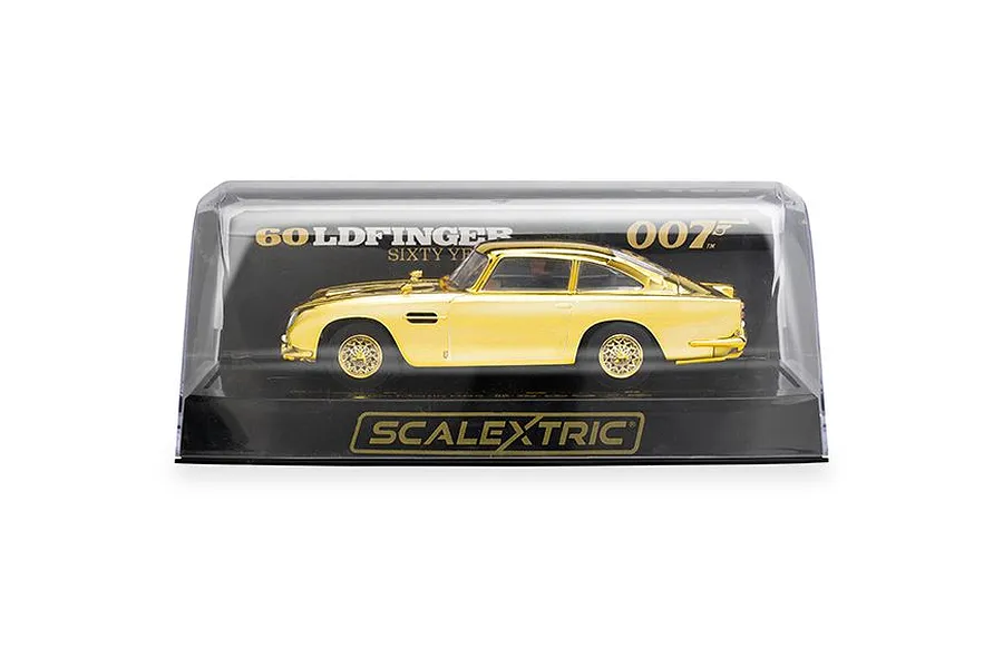 A gold-plated 1/32 scale Aston Martin DB5 slot car from Scalextric, displayed inside its clear plastic presentation case with Goldfinger 60th Anniversary branding.