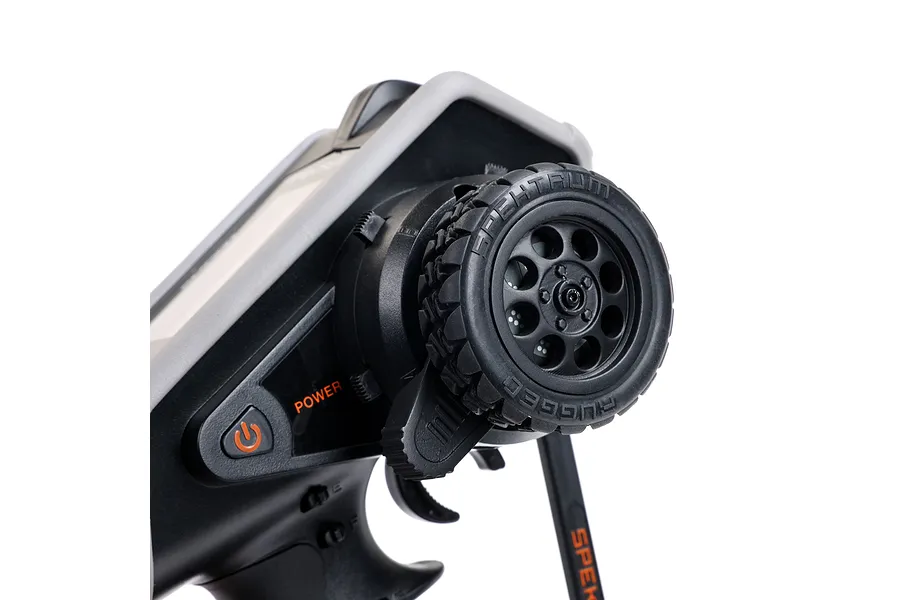 Close-up of the steering wheel and power button on a Spektrum DX Rugged RC transmitter, showing the textured rubber tire grip and orange power label.