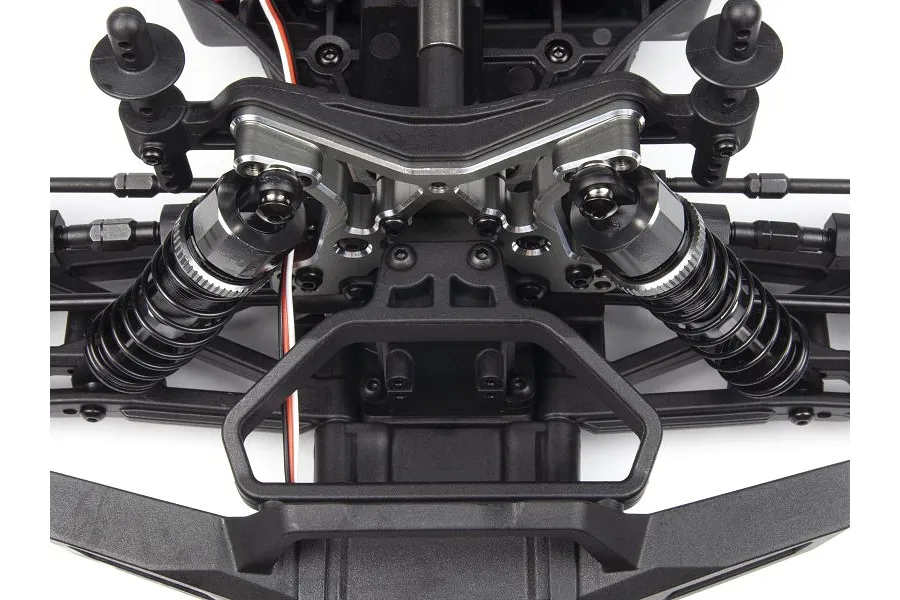 Close-up of a grey aluminium front shock tower installed on an RC car chassis with black suspension components.