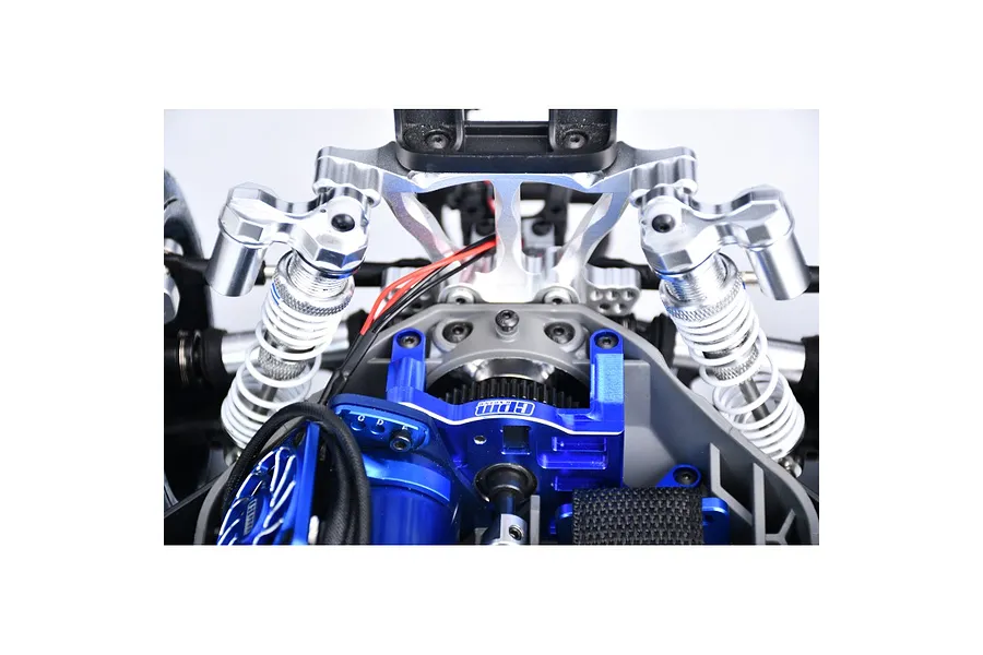 Close-up of a blue GPM Racing aluminium motor mount installed in an RC car chassis, featuring a cooling fan and silver shock absorbers.