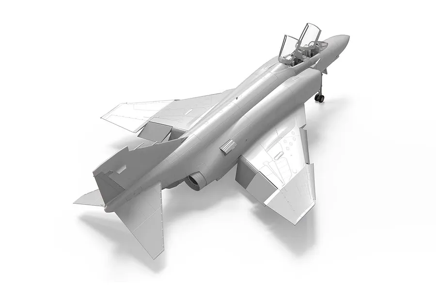 A high-angle studio shot of an unpainted, assembled plastic model of a McDonnell Douglas Phantom jet fighter on a white background.