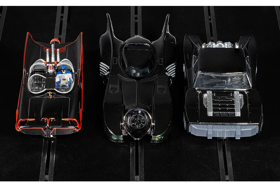 Three Scalextric 1/32 scale Batmobile slot cars from the Ultimate Collection set, displayed on a black slot car track.