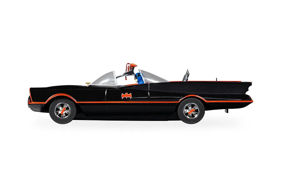 Side profile of a 1/32 scale Scalextric Batmobile slot car with black body, orange trim, and a Batman figure in the cockpit.