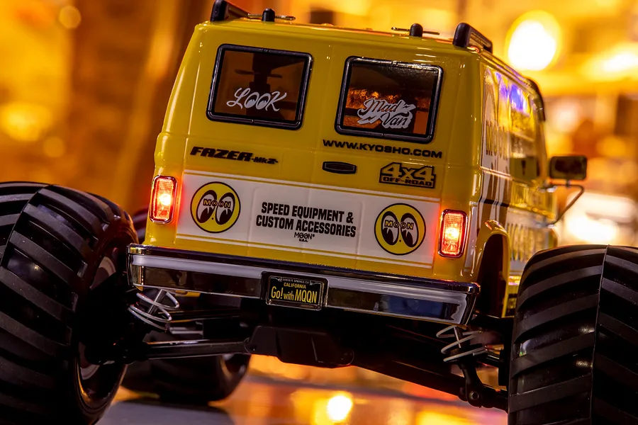 Rear view of the yellow Kyosho Fazer Mk2 Mad Van RC monster truck with Mooneyes branding and illuminated tail lights.
