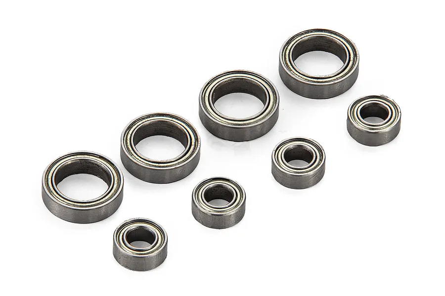 A set of eight metal shielded ball bearings of two different sizes arranged on a white background.