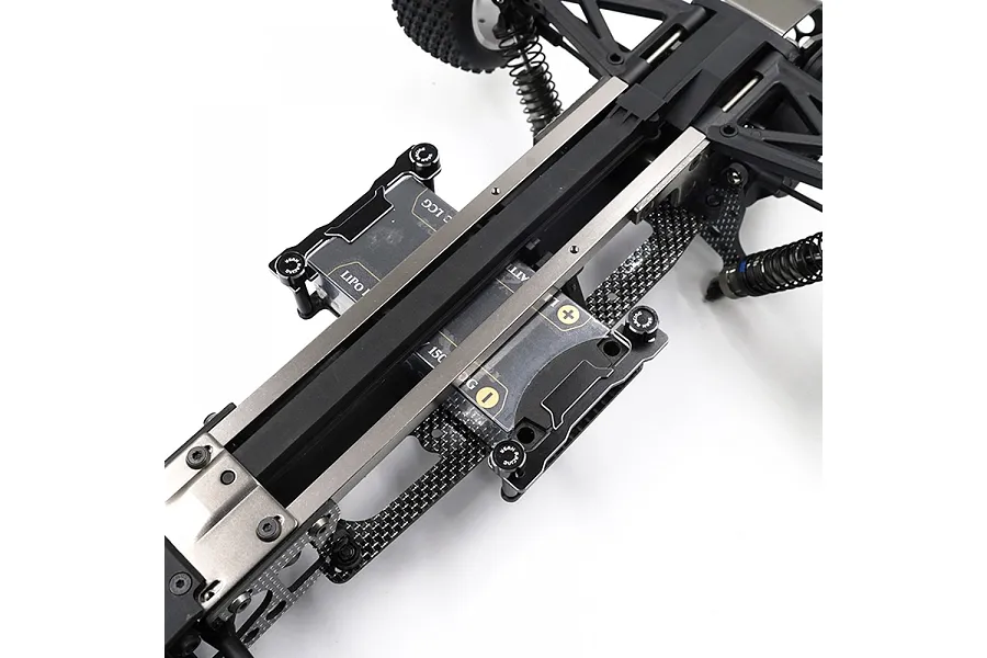 A close-up view of a Yeah Racing aluminium and carbon fibre short battery holder installed on an RC car chassis.