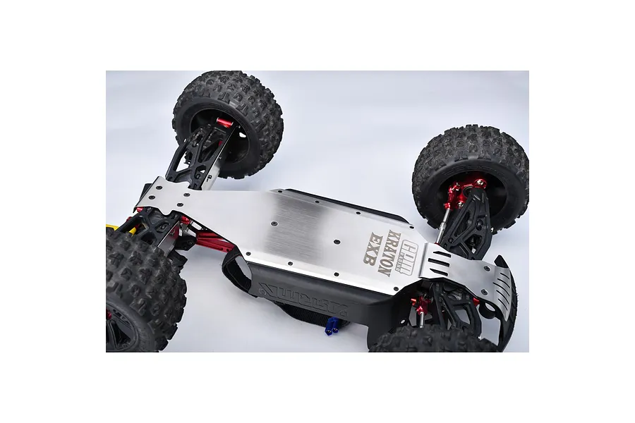 A close-up view of the underside of an RC car chassis featuring a GPM Racing stainless steel skid plate installed on an Arrma Kraton EXB.