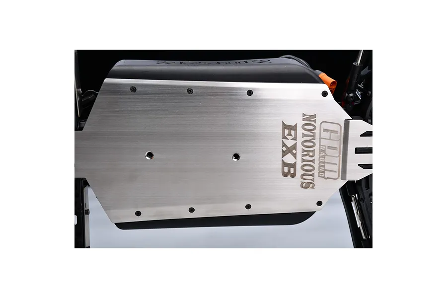 A close-up view of a GPM Racing stainless steel chassis skid plate installed on an RC vehicle, featuring laser-etched branding.