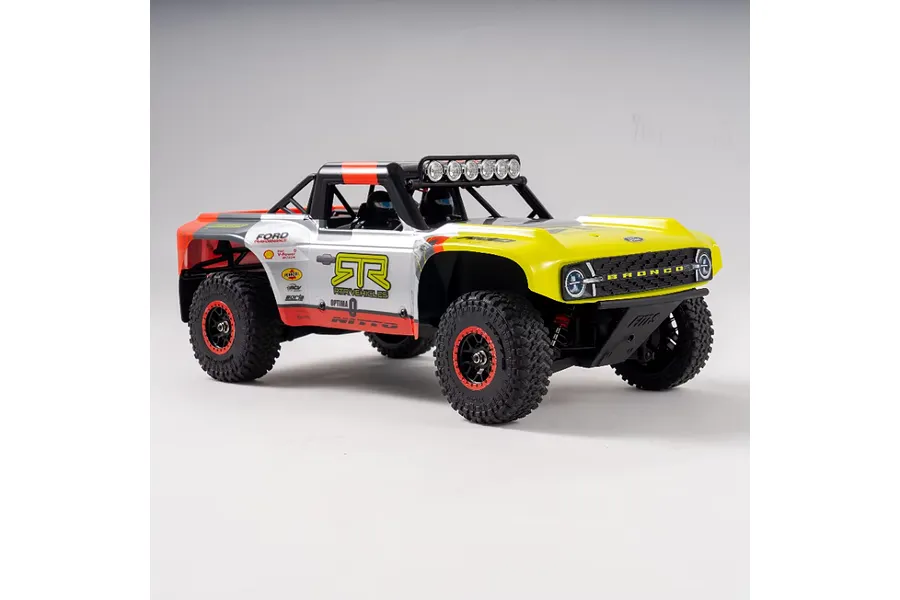 A studio shot of the FMS FSC18 Ford Bronco RC short course truck in a white, yellow, and orange livery against a plain grey background.