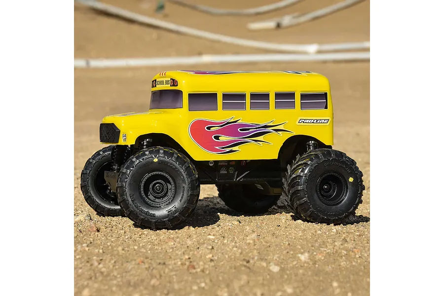 A yellow Pro-Line school bus RC body shell mounted on a monster truck chassis, sitting on a dirt track.