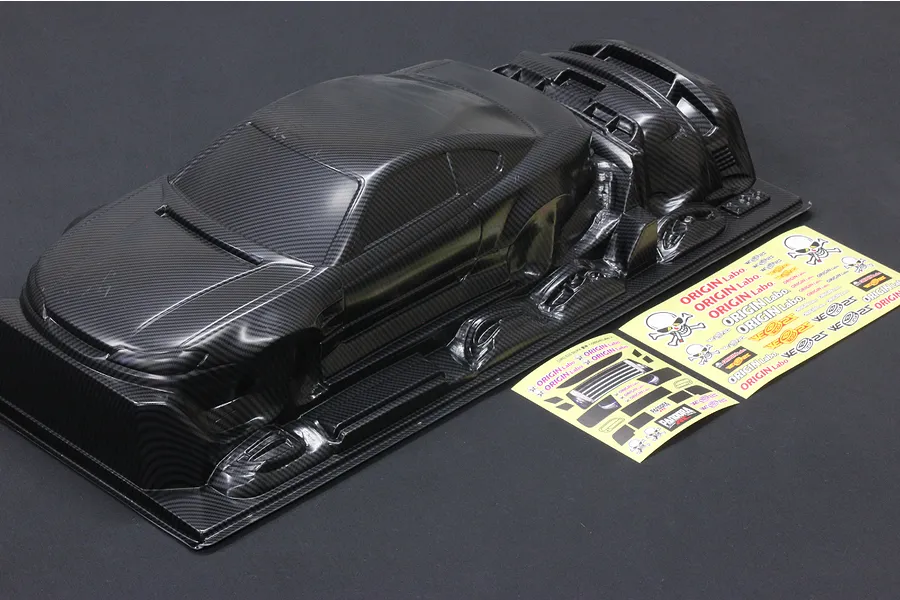 A carbon fiber patterned 1/10 scale RC Nissan S15 Silvia body shell with included decal sheets on a dark background.
