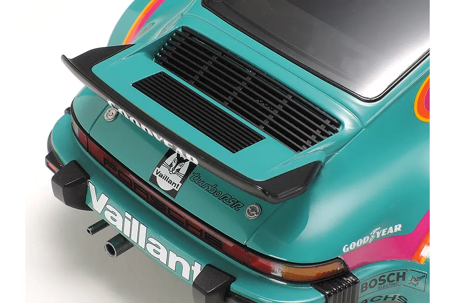Close-up of the rear section of a Tamiya 1/24 scale Porsche 934 Turbo RSR Vaillant model car, showing the spoiler, engine grille, and racing decals.