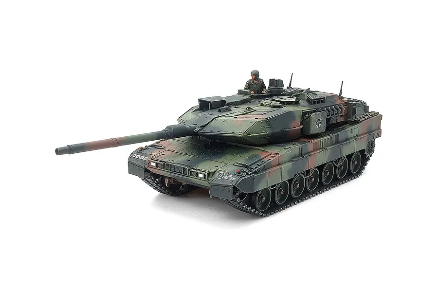 A fully assembled and painted 1/48 scale Tamiya Leopard 2 A7V model tank with a camouflage pattern and a crew figure in the hatch.