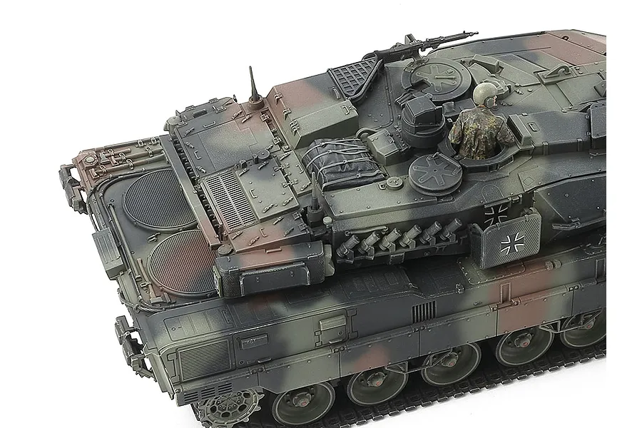 High-angle view of a Tamiya 1/48 scale Leopard 2 A7V tank model showing the turret, engine deck, and a crew member figure.