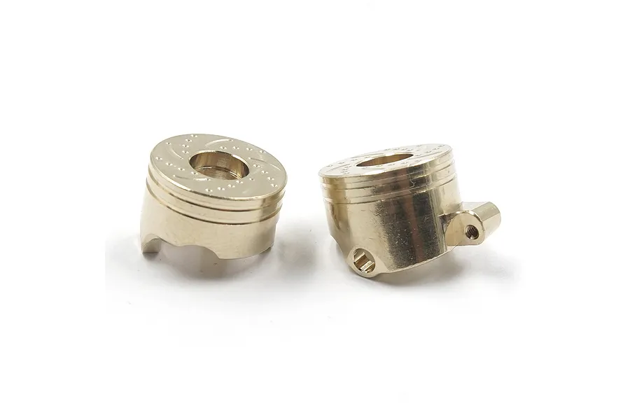 Two brass-coloured RC steering hubs with a simulated brake disc pattern on top, set against a plain white background.