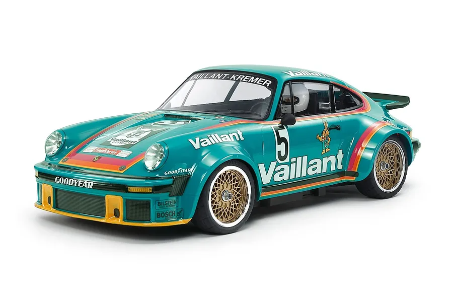 A 1/10 scale Tamiya Porsche 934 RC car in Vaillant livery, featuring a teal body with gold mesh wheels, racing decals, and a driver figure inside.