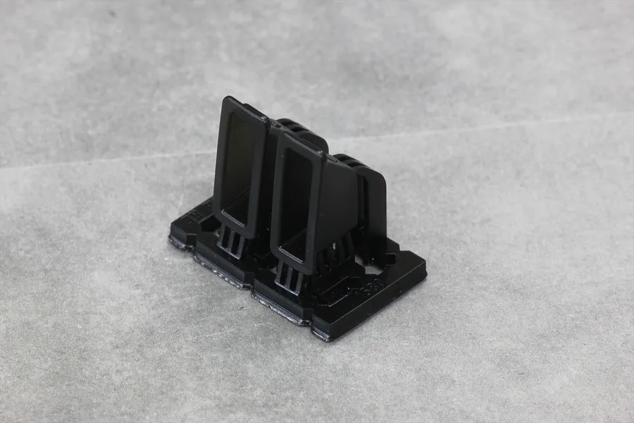 A pair of black plastic 33-type air ducts for RC car bodies, viewed from a high angle on a grey surface.