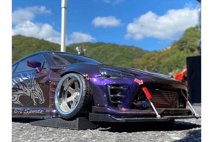 A purple RC drift car parked on a black Pandora RC plastic slope accessory outdoors.