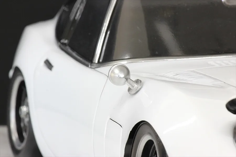 A close-up view of a silver classic-style fender mirror mounted on a white RC car body shell.