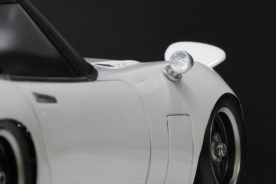 A close-up view of a white RC car body shell featuring a classic round fender-mounted side mirror.