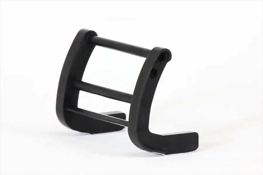 A black plastic RC grill guard accessory for 1/10 scale model cars, shown from a side angle against a white background.