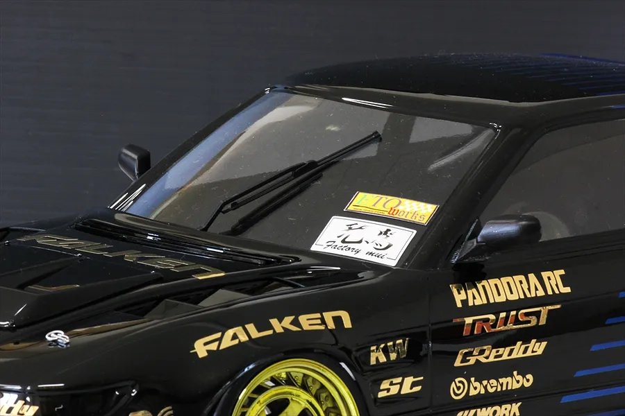 A close-up of a black RC car body shell featuring a black windscreen wiper blade installed on the front windshield.
