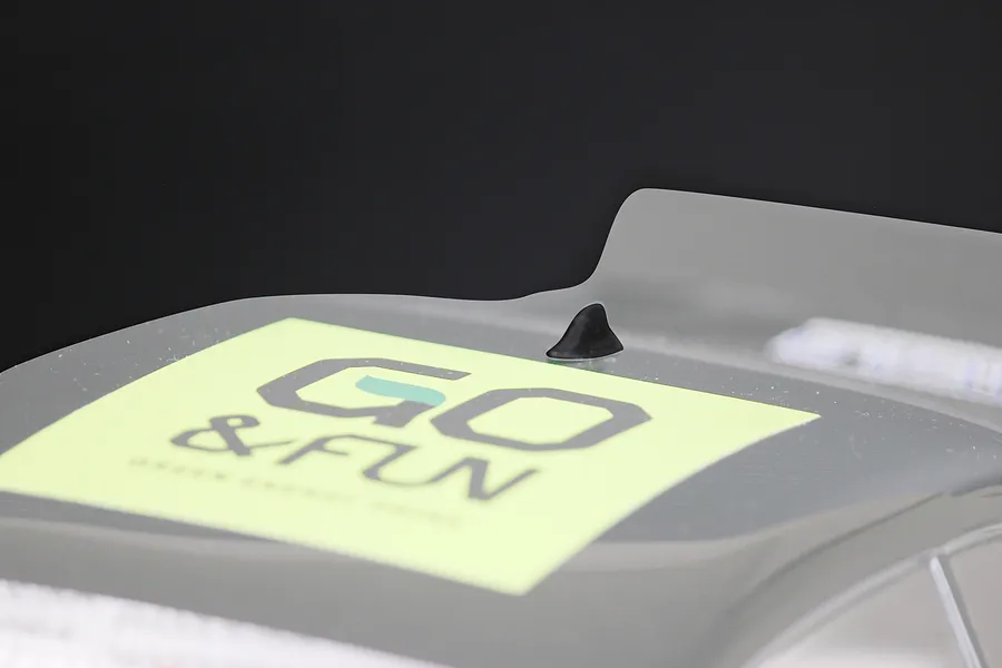 A small black shark fin style roof antenna mounted on a clear polycarbonate RC car body shell with a GO &amp; FUN sticker.